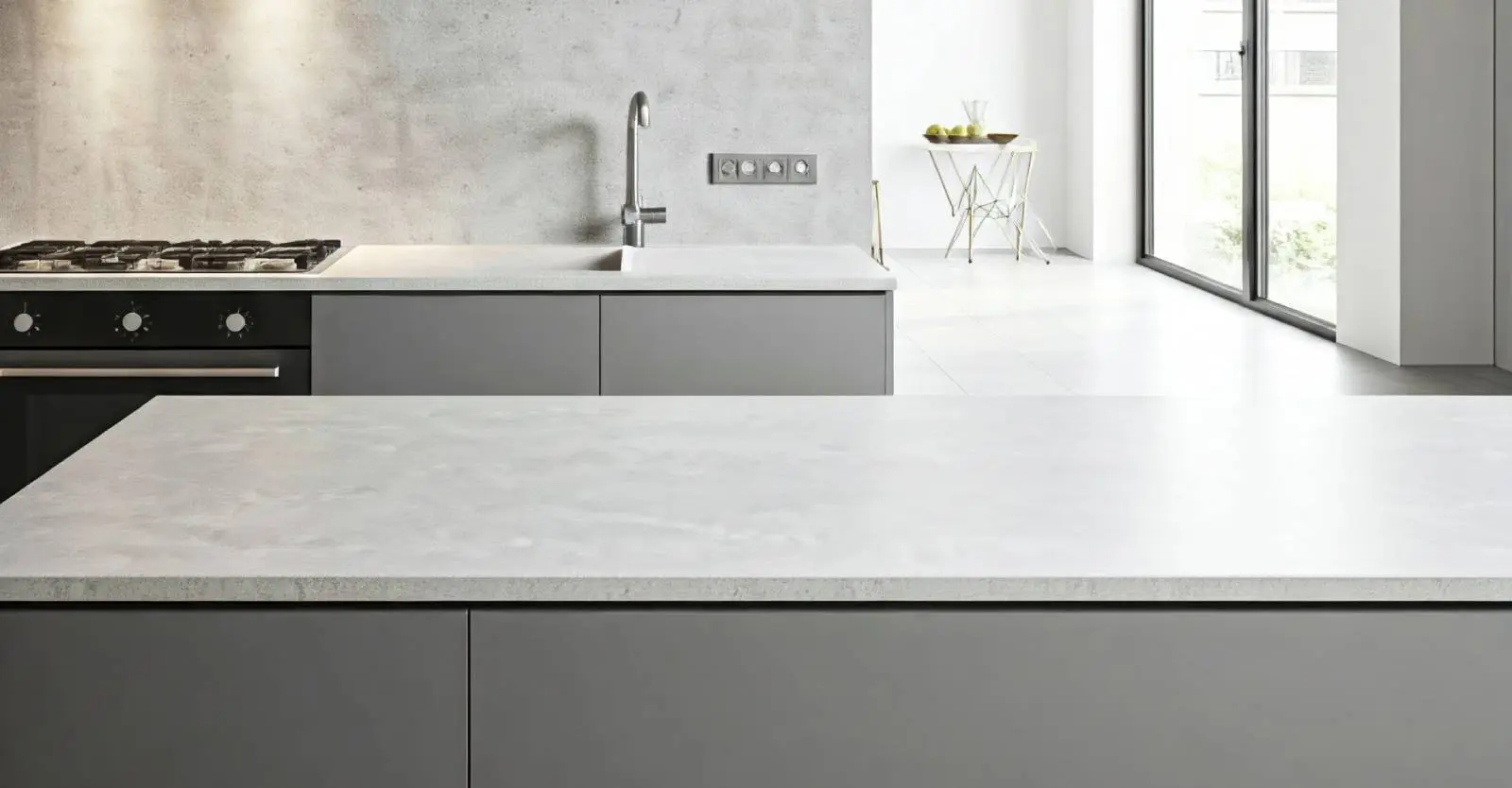 Modern kitchen interior with airy concrete wall and a large island countertop.