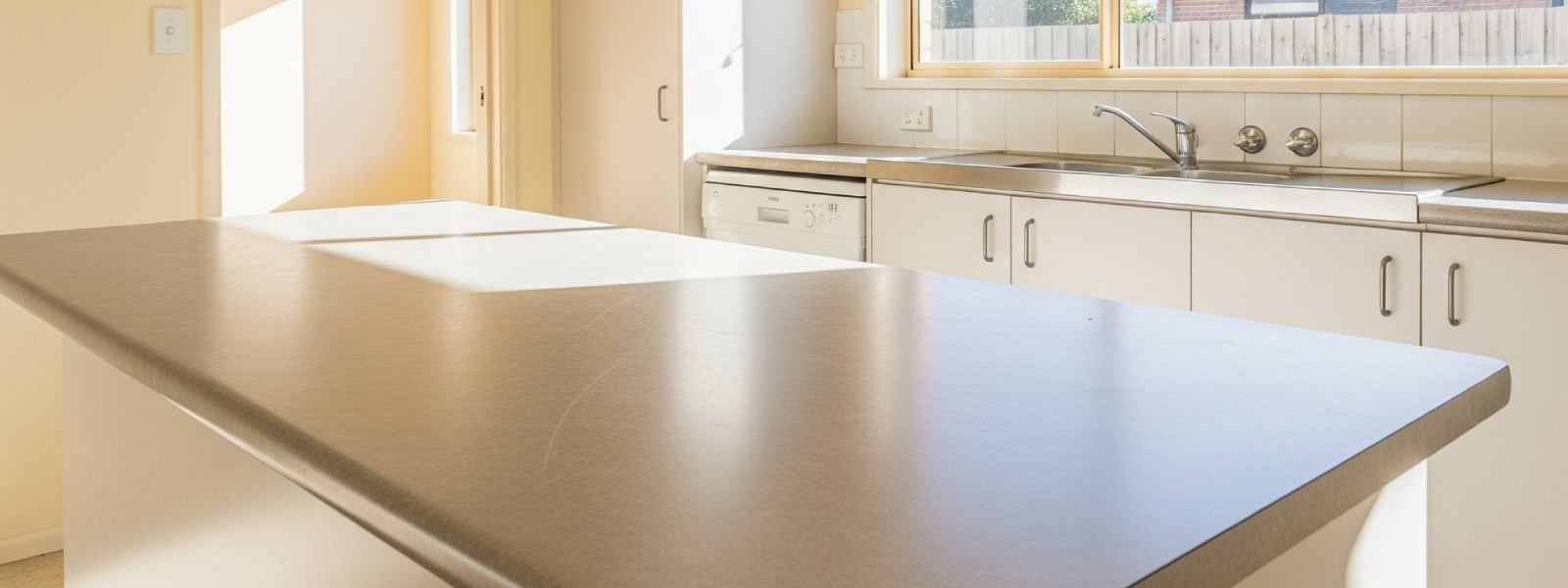 Kitchen featuring an affordable laminate benchtop with white cabinetry and stainless steel sink