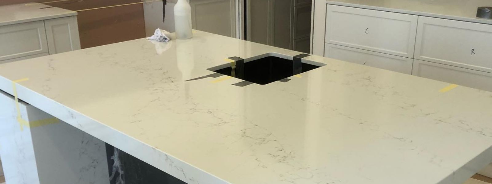 Newly installed Caesarstone benchtop with a cutout for a sink, surrounded by white cabinetry.