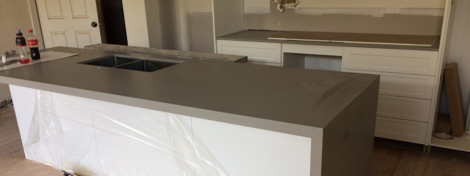 Newly installed benchtop in a modern kitchen with white cabinets and a grey countertop