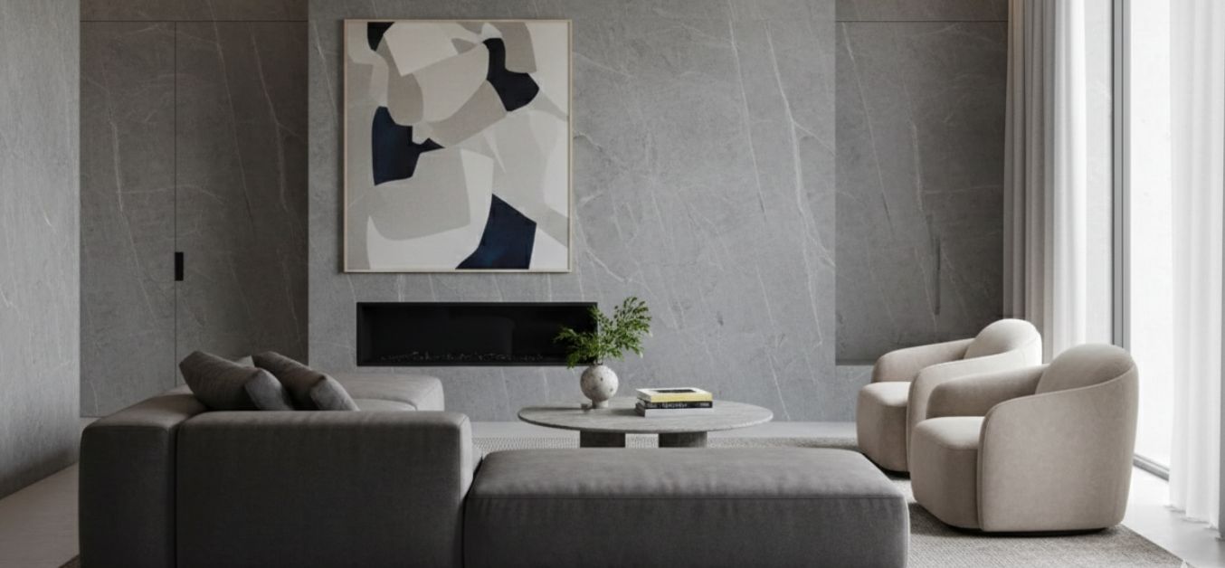 Modern minimalist living room featuring a large-format neolith stone accent wall, a low-profile charcoal sectional, and soft beige armchairs.